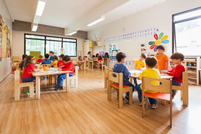 sala de aula da Beacon School com crianças sentadas em cadeiras e mesas infantis de marcenaria